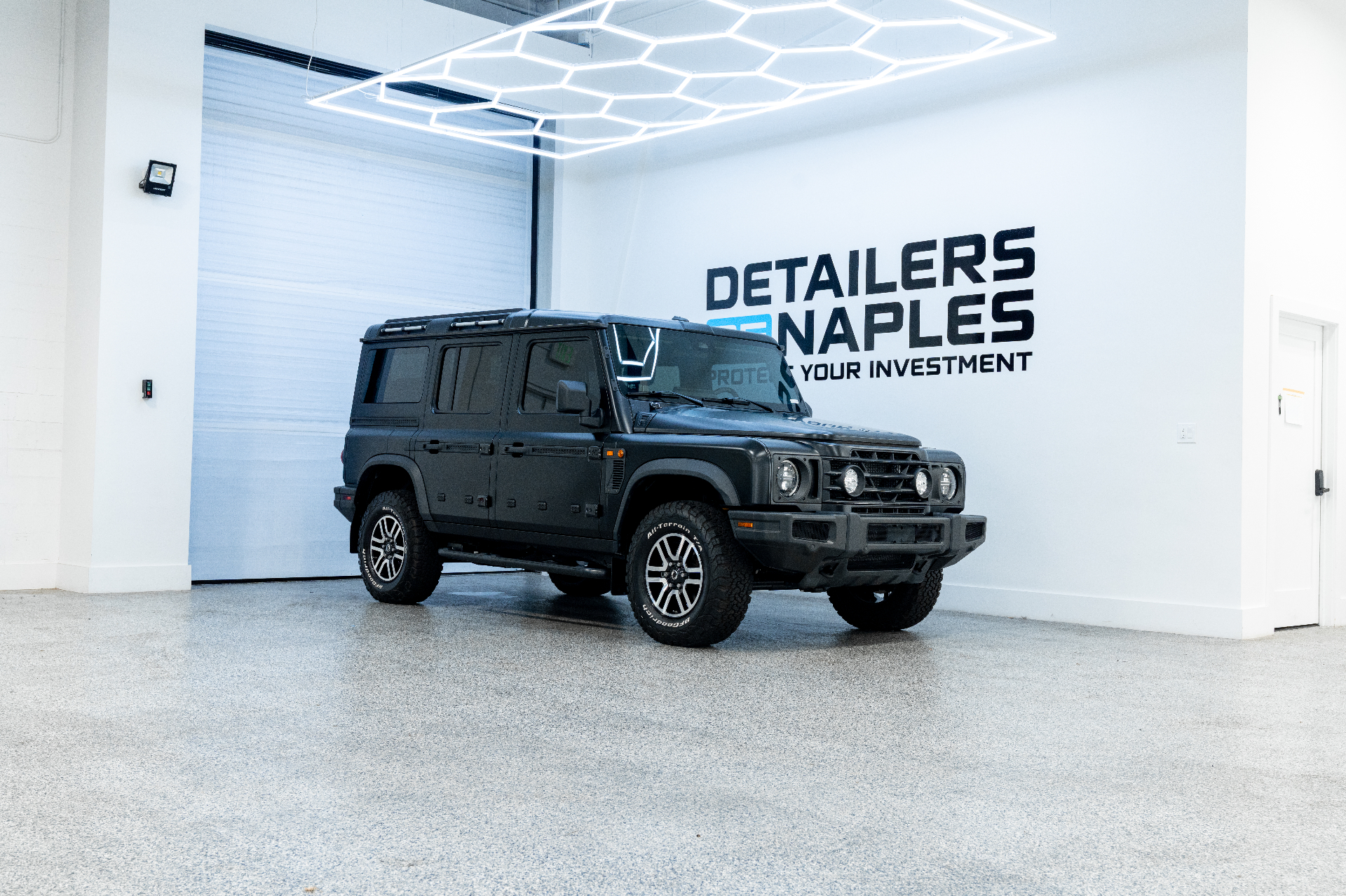 Black Land Rover Defender parked inside the Detailers of Naples shop