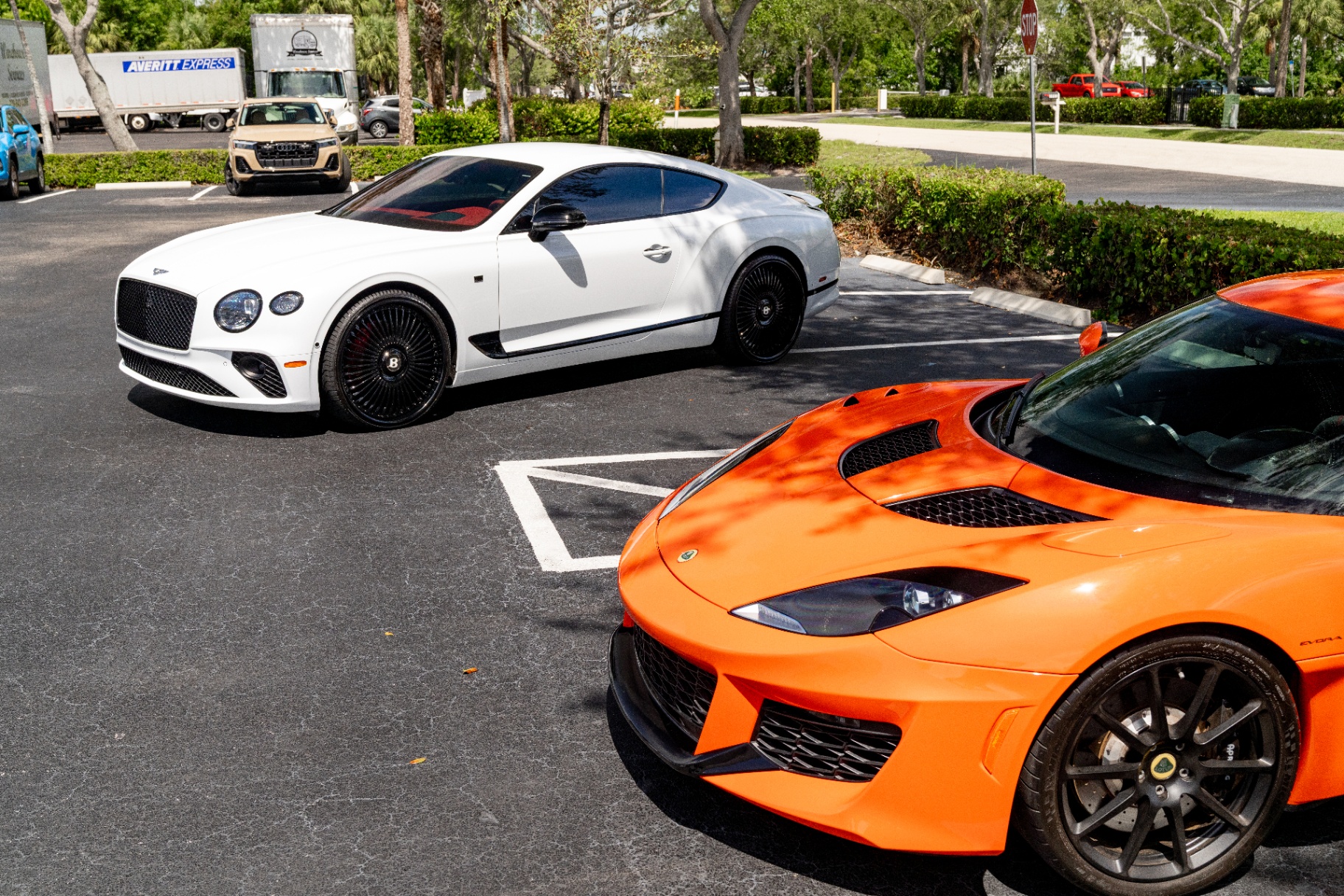 White Bentley and orange Lotus parked at the Detailers of Naples shop