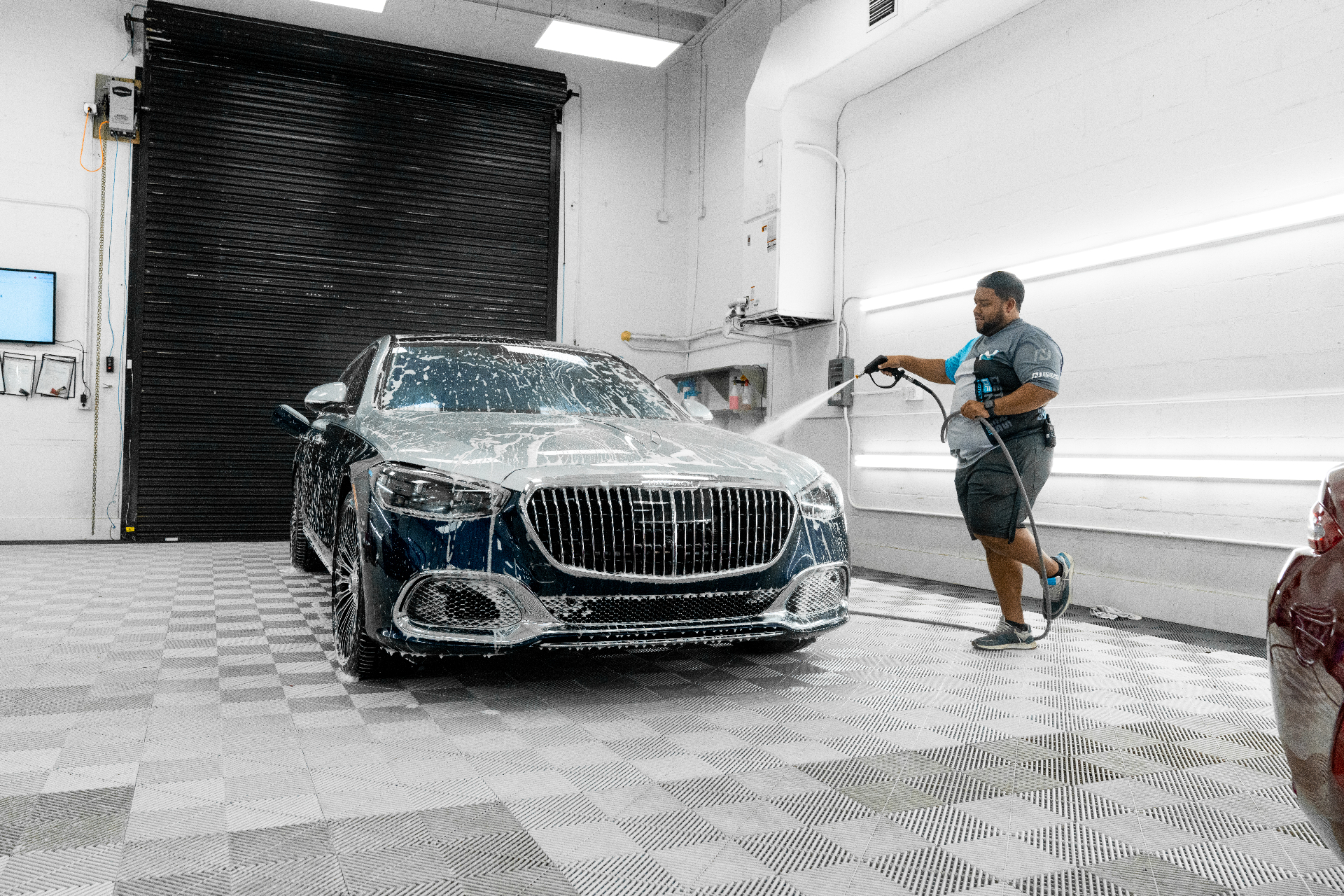 Detailers of Naples technician pressure washing a Mercedes sedan during auto detailing